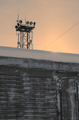 The lighting tower rises from behind an iron trailer covered in snow.