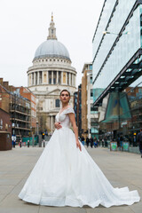 Obraz premium Young bride in white wedding dress on the square, background architecture