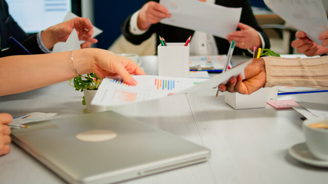 Close up of diverse startup company colleagues meeting in professional workplace, brifing and sharing ideas over financial strategy management. Multiracial business people working together at office.