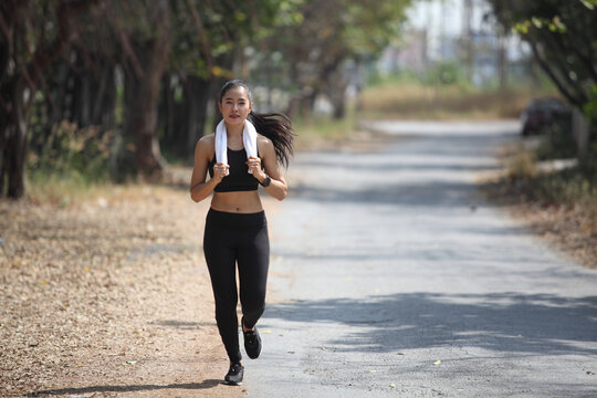 runner - woman running outdoors training for marathon run. Beautiful fit asian fitness model Sporty . Photo of attractive woman in fashionable sportswear. Dynamic movement. Sport and healthy lifestyle