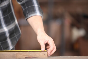 Carpenter, he is working in the workshop. Man at work on wood. Image of mature carpenter in the workshop, furniture making concept.