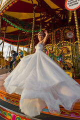 the bride sits on a carousel horse, background merry-go-round