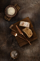 Classic Austrian strudel with apples,ice cream and sugar powder on rustic wooden plate on brown background.Top view.