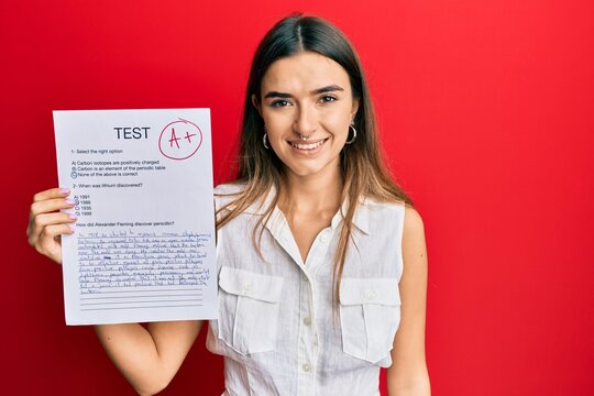 Young Hispanic Woman Showing A Passed Exam Holding Trophy Looking Positive And Happy Standing And Smiling With A Confident Smile Showing Teeth