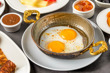 Fried eggs in a frying pan with cheese and bread for breakfast on a stone background.