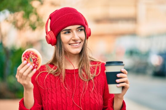 Young hispanic woman having breakfast using headphones at the city.