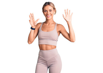 Beautiful caucasian woman wearing sportswear showing and pointing up with fingers number nine while...