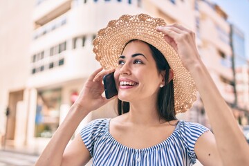 Young latin tourist girl on vacation smiling happy  talking on the smartphone at the city.