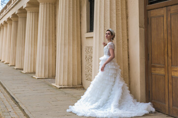 Obraz premium bride in a white wedding dress, background building with columns