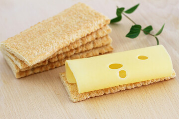 Swiss cheese on crisp bread on wooden board
