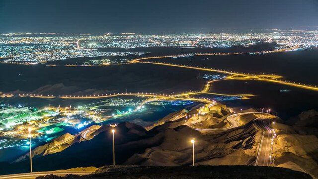 Night timelapse with rocks and curvy road on Jebel Hafeet. Mountain located primarily in the environs of Al Ain and offers an impressive view over the illuminated city. Aerial view from top