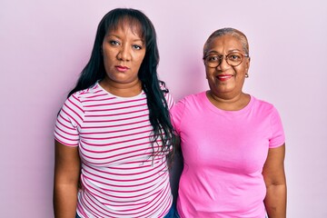 Hispanic family of mother and daughter hugging together with love thinking attitude and sober expression looking self confident