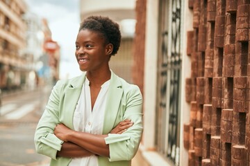 Young african american businesswoman with crossed arms smiling happy at the city