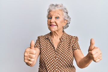 Senior grey-haired woman wearing casual clothes approving doing positive gesture with hand, thumbs...