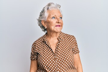 Senior grey-haired woman wearing casual clothes looking away to side with smile on face, natural expression. laughing confident.