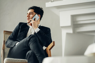 a dark-haired man of European appearance in a black business suit calls a friend. the lawyer sits in a modern office. talking on the phone with a partner. my favorite job is a manager in a bank.