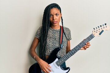 African american woman playing electric guitar skeptic and nervous, frowning upset because of problem. negative person.