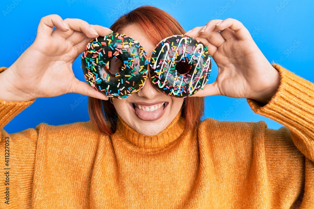 Canvas Prints beautiful redhead woman holding tasty colorful doughnuts on eyes sticking tongue out happy with funn