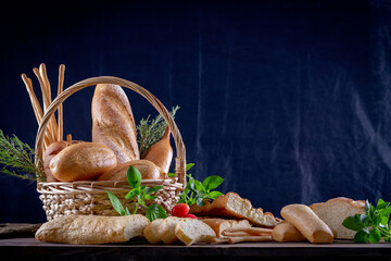Variety of breads in basket on wooden table in dark background. Bakery Assortment.