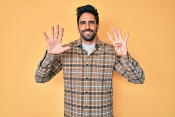 Handsome hispanic man with beard wearing casual clothes showing and pointing up with fingers number...