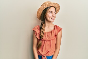 Beautiful brunette little girl wearing summer hat looking away to side with smile on face, natural...