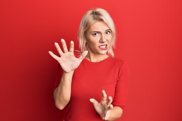 Young blonde girl wearing casual clothes disgusted expression, displeased and fearful doing disgust...