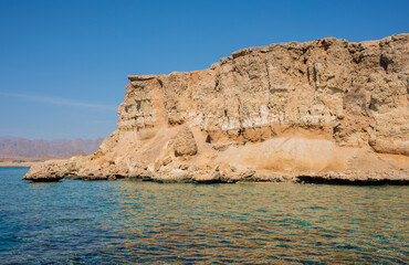 beautiful seascape with clear turquoise and blue water and bright yellow rocks off the coast of Sharm El Sheikh in egypt
