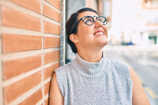 Young plus size woman smiling happy leaning on the wall at the city.