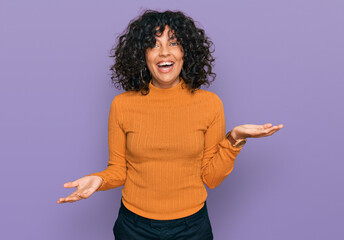 Young hispanic woman wearing casual clothes smiling cheerful with open arms as friendly welcome, positive and confident greetings