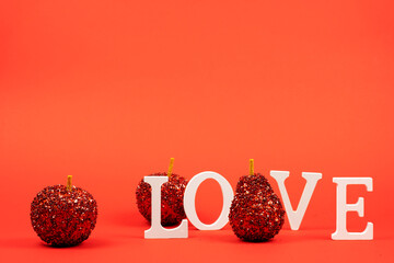 The word love with red decorative apples on a red background, Greeting card