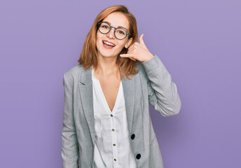 Young caucasian woman wearing business style and glasses smiling doing phone gesture with hand and fingers like talking on the telephone. communicating concepts.