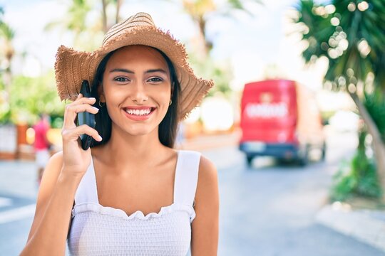 Young latin girl wearing summer style talking on the smartphone at street of city.