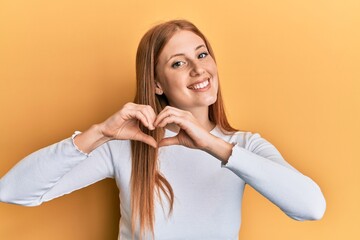 Young irish woman wearing casual clothes smiling in love doing heart symbol shape with hands....