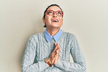 Young caucasian woman wearing casual clothes and glasses begging and praying with hands together...