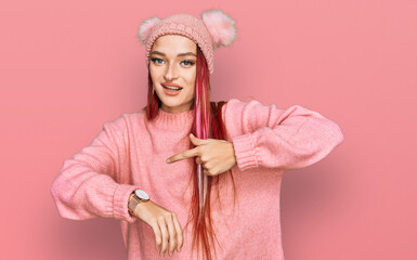 Young caucasian woman wearing casual clothes and wool cap in hurry pointing to watch time, impatience, upset and angry for deadline delay