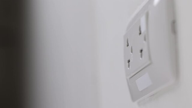 Hand remove Electric plug on socket. Electrical equipment, electrical wires and power strips in the house. Earth Hour saving electrical energy.