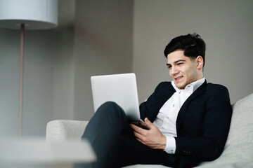 works on a laptop computer, sits in the office on a comfortable sofa. Favorite job on the financial exchange. portrait of a business man of Italian appearance. in a stylish suit.