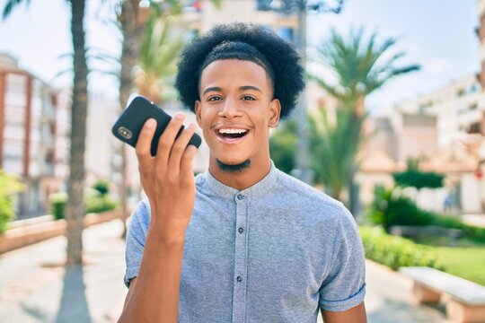 Young african american man smiling happy sending audio message using smartphone at the city.