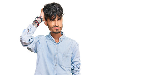 Young hispanic man wearing casual clothes confuse and wondering about question. uncertain with...