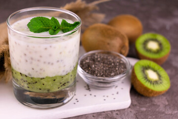 Yogurt with kiwi and chia seeds in a glass.
Close-up.