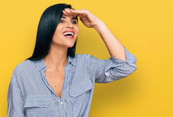 Young caucasian woman wearing casual clothes very happy and smiling looking far away with hand over head. searching concept.