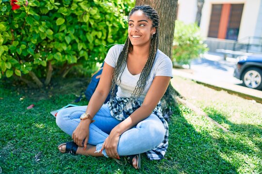 Young african american student woman smiling happy sitting on the grass at the university campus
