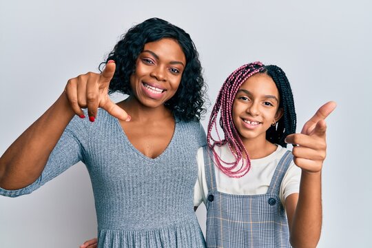 Beautiful african american mother and daughter wearing casual clothes and hugging pointing fingers to camera with happy and funny face. good energy and vibes.