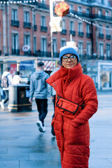 happy woman in red coat, hat walking around city in cold weather