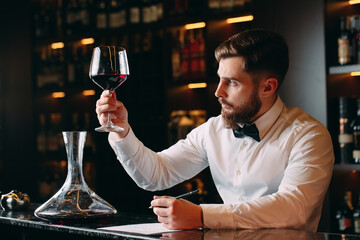 Young handsome man sommelier tasting red wine in cellar.