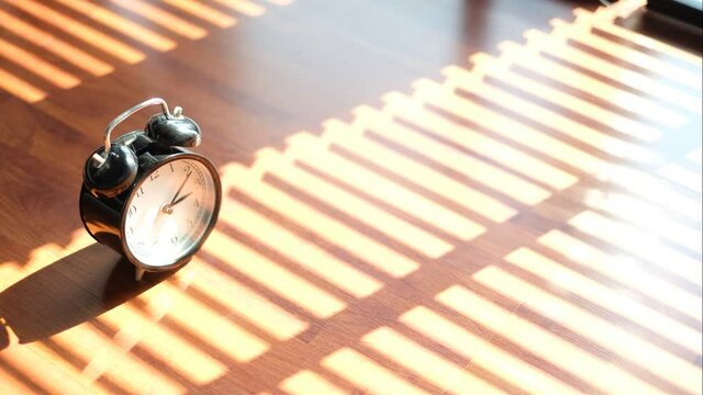 Black clock Time was walking in the afternoon until evening and the sunlight on the wooden floor shaded through the blinds.