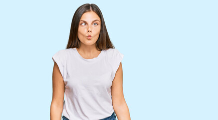 Young caucasian woman wearing casual white tshirt making fish face with lips, crazy and comical gesture. funny expression.