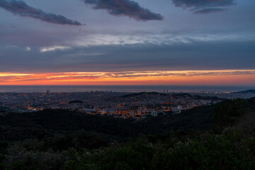 Sunrise on a spring day in the city of Barcelona. We can see the sky, with some clouds that light up like fire, with the sunlight. The water of the Mediterranean Sea, completely flat.