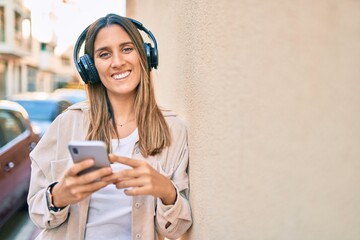 Young caucasian woman smiling happy using smartphone and headphones at the city.