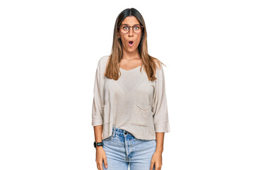 Young woman wearing casual clothes and glasses afraid and shocked with surprise expression, fear and excited face.